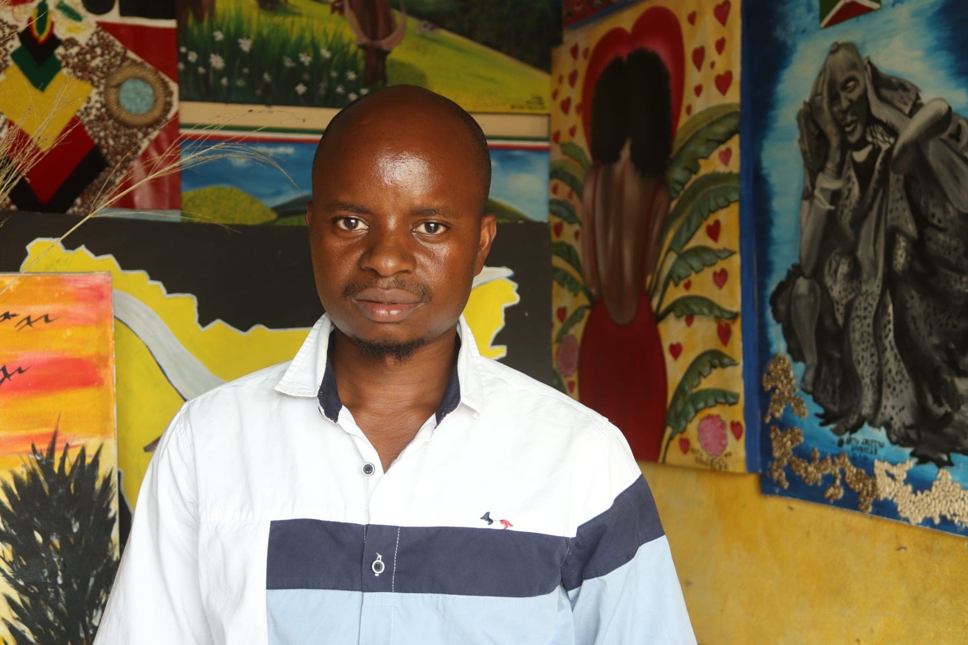 Young artist standing in his studio among his paintings